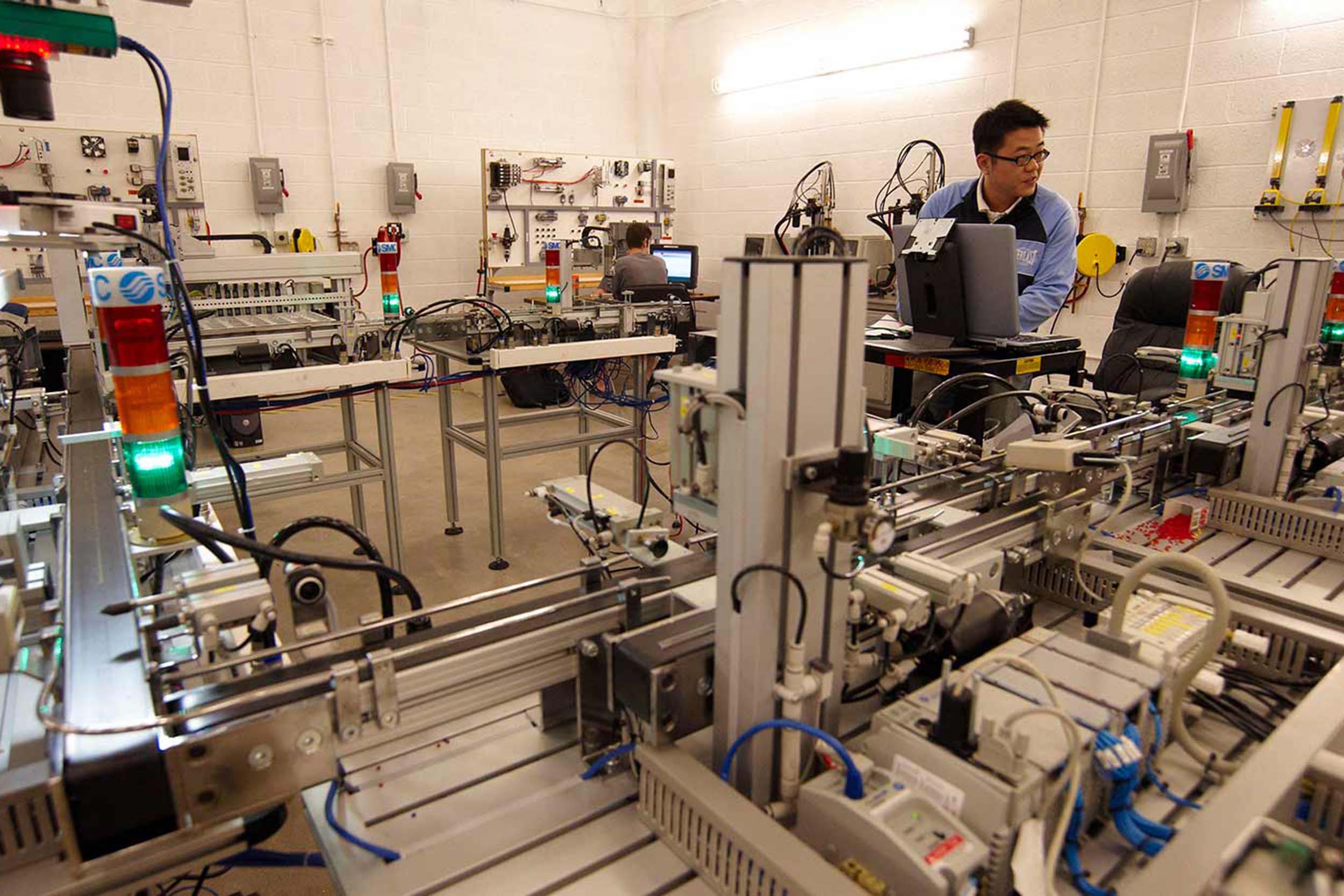 A student works in a systems engineering lab surrounded by several complex mechanical systems