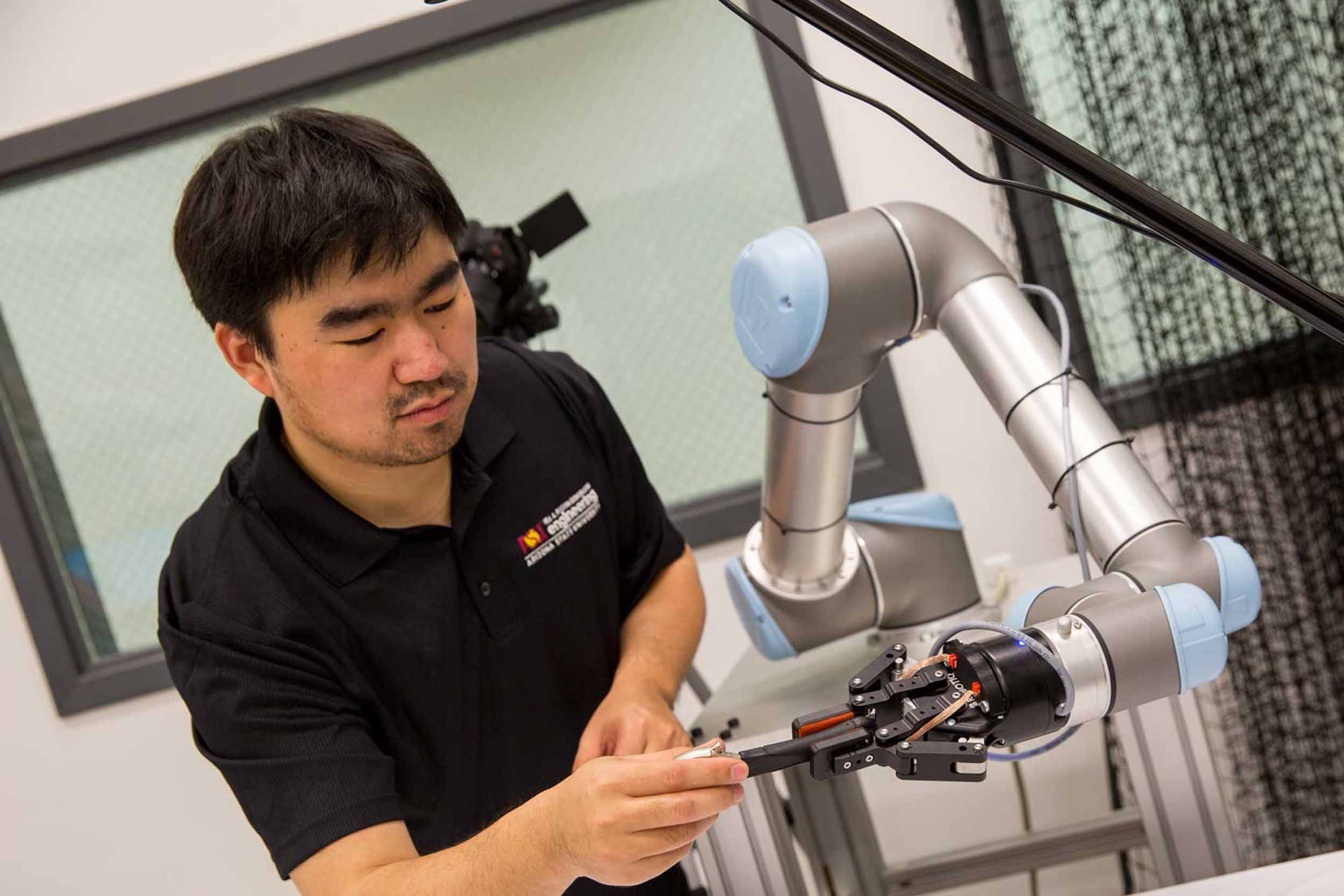 a researcher in Wenlong Zhang's lab handles a robotic arm