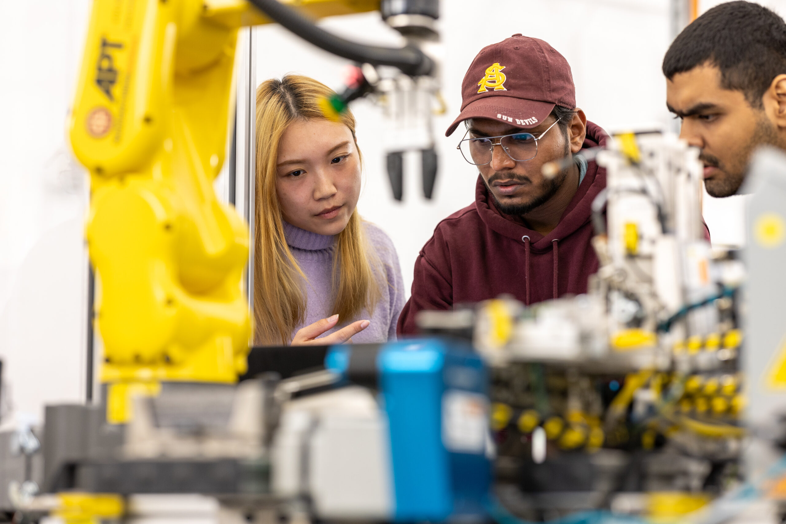 Student observe the work of a FANUC robot in the Industrial Automation and Robotics Lab located on the Polytechnic campus.