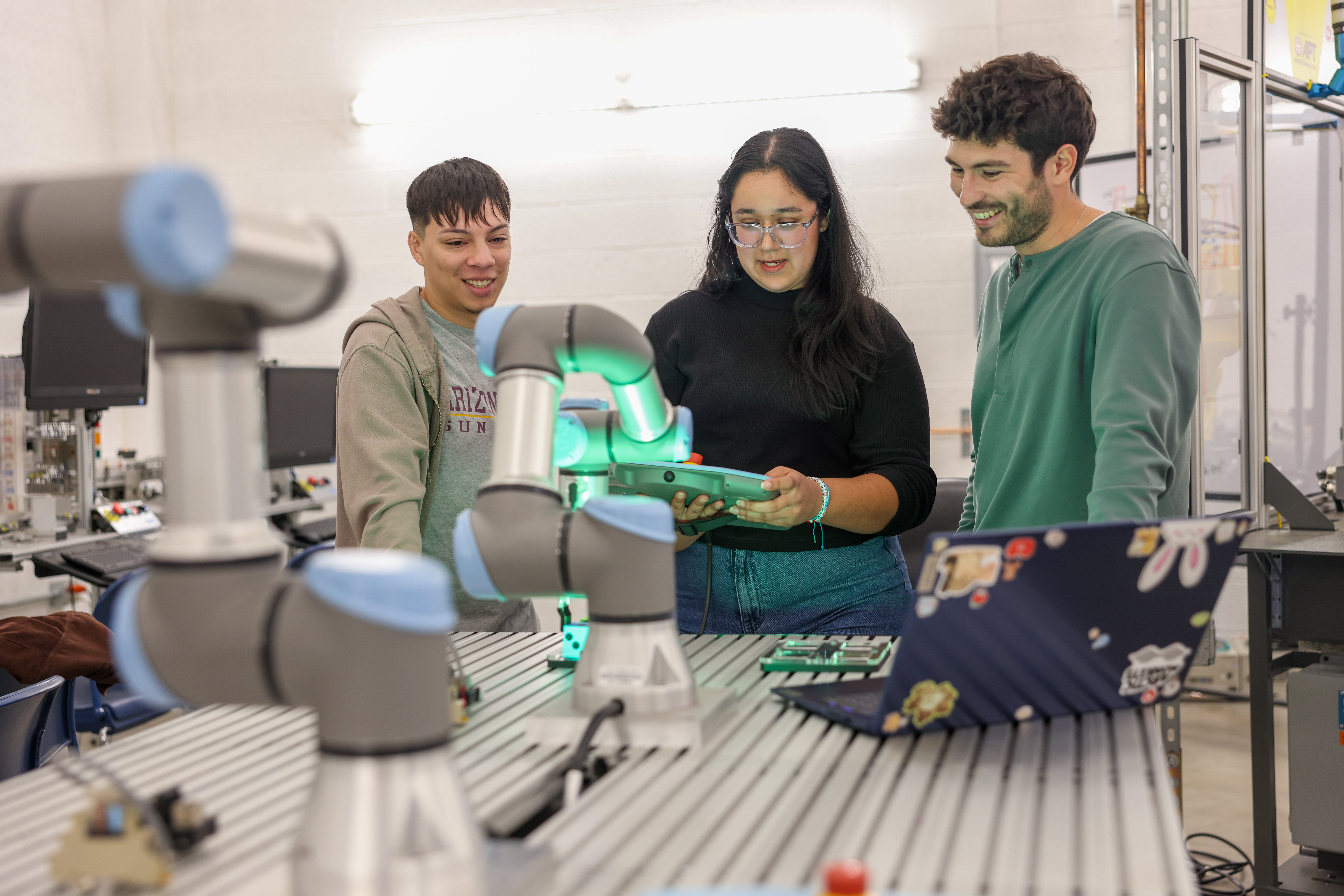 Arizona State University Polytechnic students in the Simulation Building engage in advanced robotics coursework, programming machines to perform precise, real-world actions.