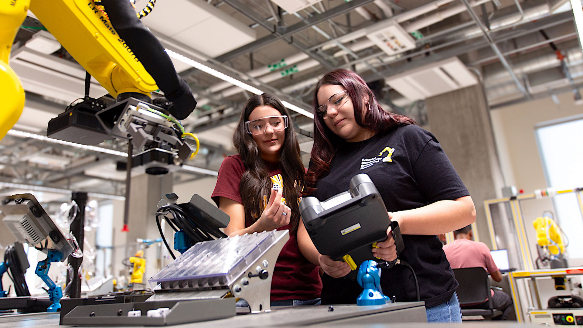 Jenavieve Echegaray (left) and Lexana Echegaray (right), manufacturing engineering students in the School of Manufacturing Systems and Networks, part of the Ira A. Fulton Schools of Engineering at Arizona State University, operate a teach pendant for a FANUC robotic arm in the Robotics Systems Instructional Lab, located in the Interdisciplinary Science and Technology Building 12, or ISTB 12, on the Polytechnic campus at ASU. Photographer: Aisha Kaddi/ASU